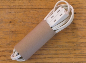 a toilet paper tube is reused to store wires and cords